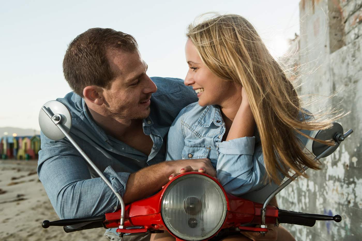 Engaged couple sitting on a red Vespa at St James in Cape Town