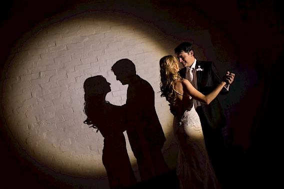 A creative shot capturing a spotlight on the bride and groom as they share an intimate dance together – Photo by Greg Lumley.