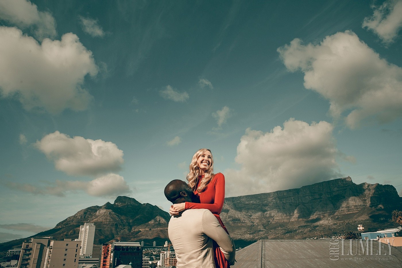Man picks his fiance up in front of a magnificent table mountain backdrop
